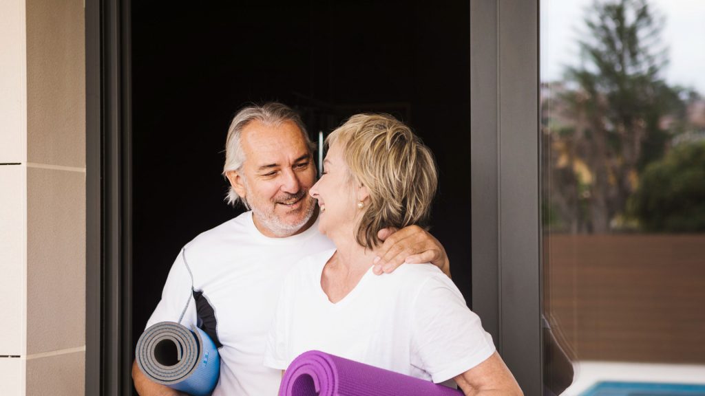 Older couple smiling and holding exercise mats